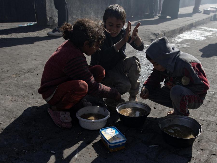 I bambini palestinesi sfollati  mangiano il cibo fornito da un gruppo di giovani palestinesi, nel campo profughi di Rafah, nel sud della Striscia di Gaza. EPA/HAITHAM IMAD