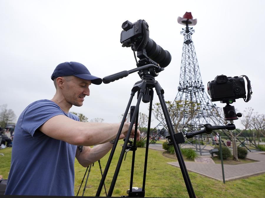 Kien McKellar di Washington D.C., prepara le sue telecamere durante un evento di osservazione dell’eclissi di fronte alla Torre Eiffel, a Parigi, Texas. (AP Photo/Tony Gutierrez)