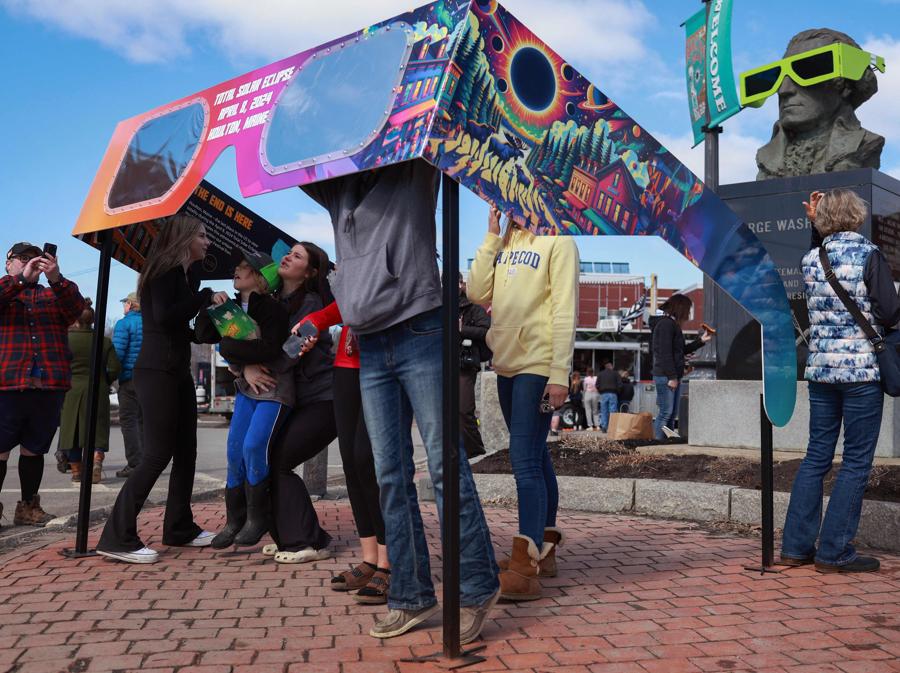 I visitatori guardano attraverso un paio di occhiali da eclissi di grandi dimensioni allestiti nella piazza della città, a Houlton, nel Maine. Joe Raedle/Getty Images/AFP