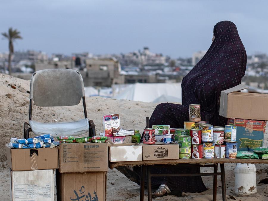 Una donna palestinese sfollata siede accanto alla sua bancarella di cibo sulla spiaggia nel campo profughi di Rafah, nel sud della Striscia di Gaza'. EPA/HAITHAM IMAD