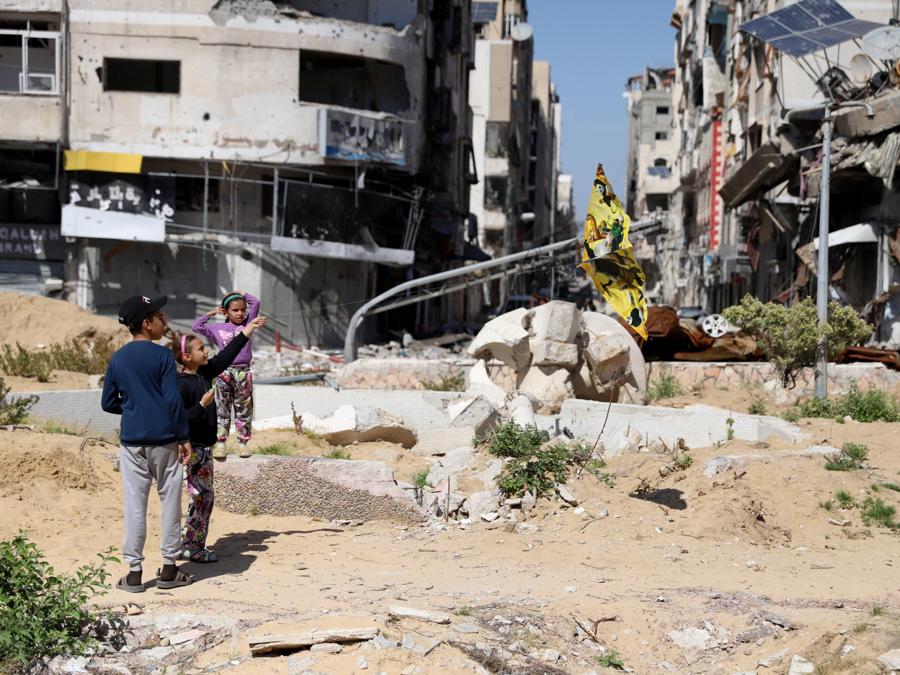 Bambini fanno volare un aquilone nella Piazza del Milite Ignoto,  vicino ai resti del Consiglio Legislativo Palestinese (PLC) nel quartiere di Remal, dopo che fu distrutto dall’esercito israeliano. EPA/MOHAMED HAJJAR