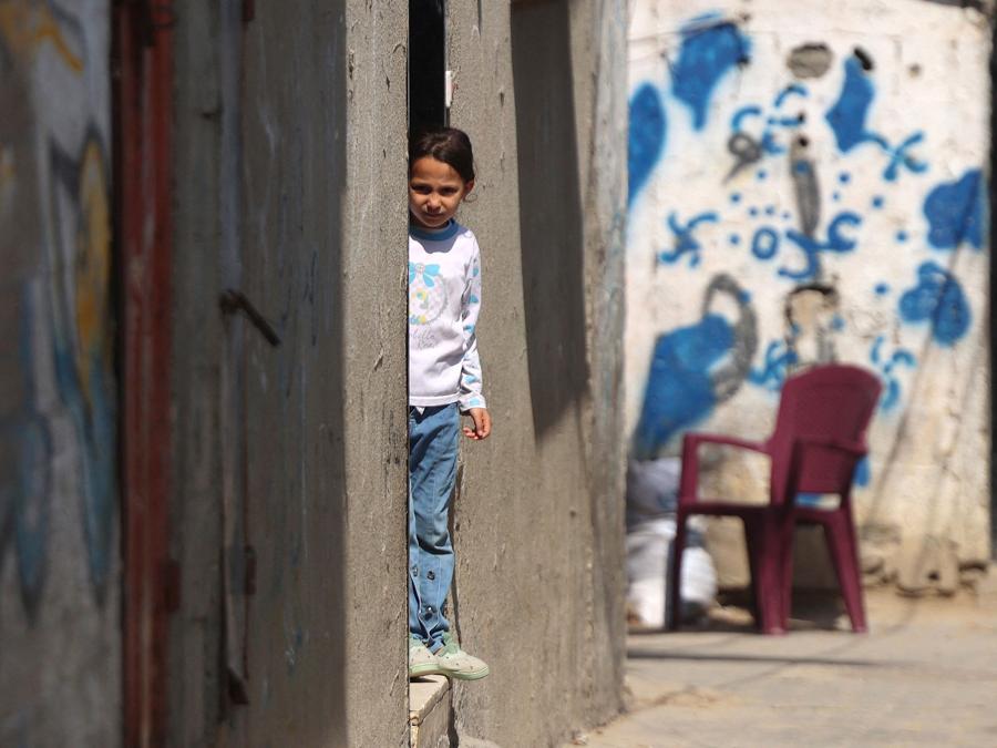 Una ragazza palestinese si trova all’ingresso di un edificio, nel campo profughi di Nuseirat, nel centro di Gaza. (Photo by AFP)