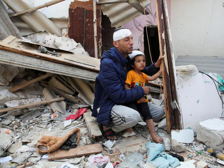 Un palestinese ferito, con in braccio il figlio ferito, piange sul luogo di un attacco israeliano contro una casa, a Rafah, nel sud della Striscia di Gaza. REUTERS/Hatem Khaled