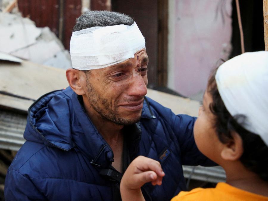 Un palestinese ferito, con in braccio il figlio ferito, piange sul luogo di un attacco israeliano contro una casa, a Rafah, nel sud della Striscia di Gaza. REUTERS/Hatem Khaled