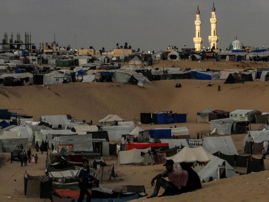 La luce illumina i minareti della moschea di al-Taiba al tramonto davanti alle tende dei palestinesi sfollati in un campo a Rafah, nel sud della Striscia di Gaza. (Photo by AFP)