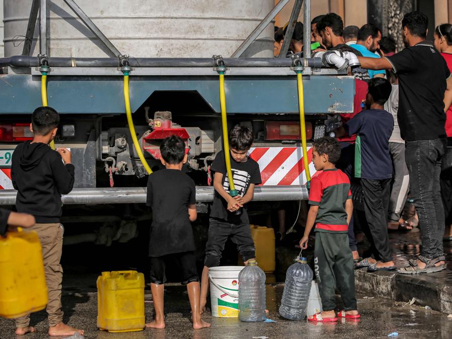 Bambini riempiono taniche e contenitori d’acqua dalla cisterna in un campo che ospita palestinesi sfollati a Rafah, nel sud della Striscia di Gaza. (Photo by AFP)