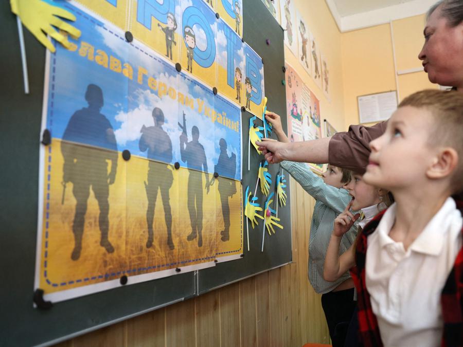 L’insegnante di scuola elementare Natalya Pyasetska insegna ai suoi alunni durante una lezione dedicata al Giorno degli Eroi presso la 61a scuola secondaria di Kiev. (Photo by Anatolii STEPANOV / AFP)