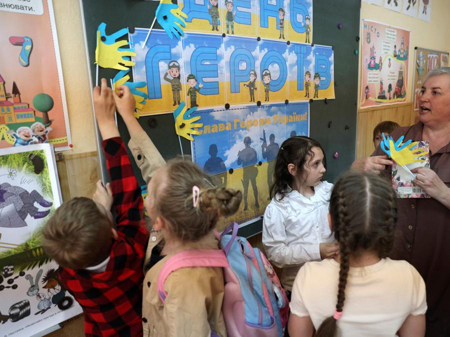 L’insegnante di scuola elementare Natalya Pyasetska insegna ai suoi alunni durante una lezione dedicata al Giorno degli Eroi presso la 61a scuola secondaria di Kiev. (Photo by Anatolii STEPANOV / AFP)
