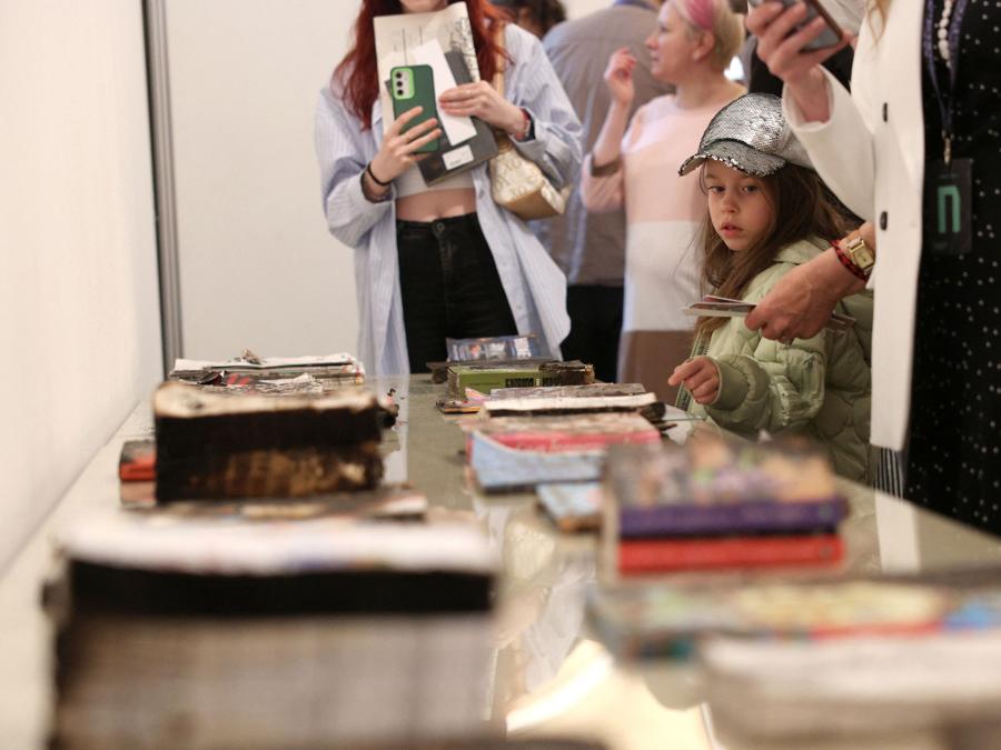 I visitatori osservano i libri danneggiati della casa editrice di Kharkiv, distrutta dai bombardamenti russi, durante l’apertura del forum annuale degli editori “Book Arsenal” a Kiev. (Photo by Anatolii STEPANOV / AFP)