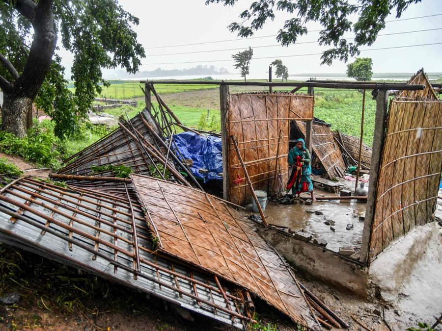 Una donna raccoglie vestiti dalla sua casa danneggiata nella zona di Hatisila, alla periferia di Guwahati, in seguito allo sbarco del ciclone Remal in India. Il ciclone Remal, che si è abbattuto sulle pianure del Bangladesh e sulla vicina India la sera del 26 maggio con violente tempeste e onde che si infrangono, ha provocato la morte di almeno 38 persone, distrutto migliaia di case, distrutto dighe marine e allagato città nei due paesi. (Photo by Biju BORO / AFP)