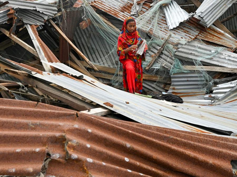 Una ragazza cammina nella sua casa danneggiata dopo l’abbattimento del ciclone Remal a Patuakhali. Il ciclone Remal, che si è abbattuto sulla pianura del Bangladesh e sulla vicina India la sera del 26 maggio con violente tempeste e onde che si infrangono, ha provocato la morte di almeno 21 persone, distrutto migliaia di case, distrutto dighe marine e allagato città nei due paesi. (Photo by Munir Uz Zaman / AFP)