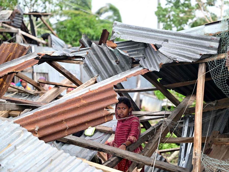 Una ragazza cammina in mezzo alla sua casa danneggiata dopo l’atterraggio del ciclone Remal a Patuakhali il 28 maggio 2024. Il ciclone Remal, che si è abbattuto sulle zone basse del Bangladesh e sulla vicina India la sera del 26 maggio con violente tempeste e onde che si infrangono, ha provocato la morte di almeno 21 persone , hanno distrutto migliaia di case, distrutto dighe marittime e allagato città nei due paesi. (Photo by Munir Uz Zaman / AFP)