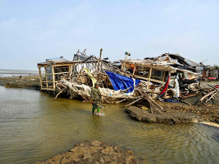 Una donna passa davanti a un negozio danneggiato dopo l’atterraggio del ciclone Remal a Patuakhali il 29 maggio 2024. Il ciclone Remal, che si è abbattuto sulle zone basse del Bangladesh e sulla vicina India la sera del 26 maggio con violente tempeste e onde che si infrangono, ha provocato la morte di almeno 38 persone, ha distrutto migliaia di case, distrutto dighe marittime e allagato città nei due paesi . (Photo by Munir Uz Zaman / AFP)