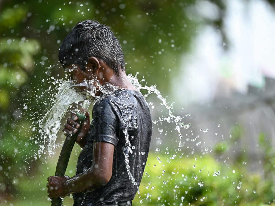 Un ragazzo gioca con l’acqua durante una calda giornata estiva a Chennai. (Photo by R.Satish BABU / AFP)