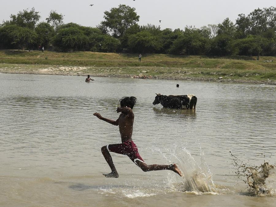 Un bambino corre nell’acqua per rinfrescarsi dal caldo soffocante di Nuova Delhi. (AP Photo/Manish Swarup)