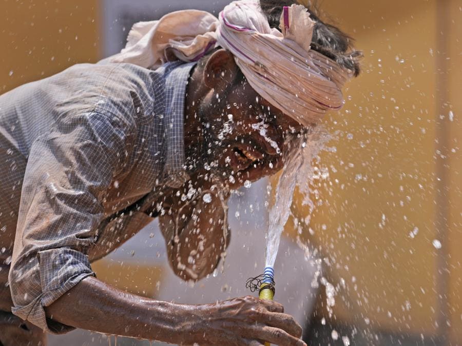 Un uomo si spruzza acqua sul viso mentre cerca di rinfrescarsi in una calda giornata estiva, a Lucknow. (AP Photo/Rajesh Kumar Singh)
