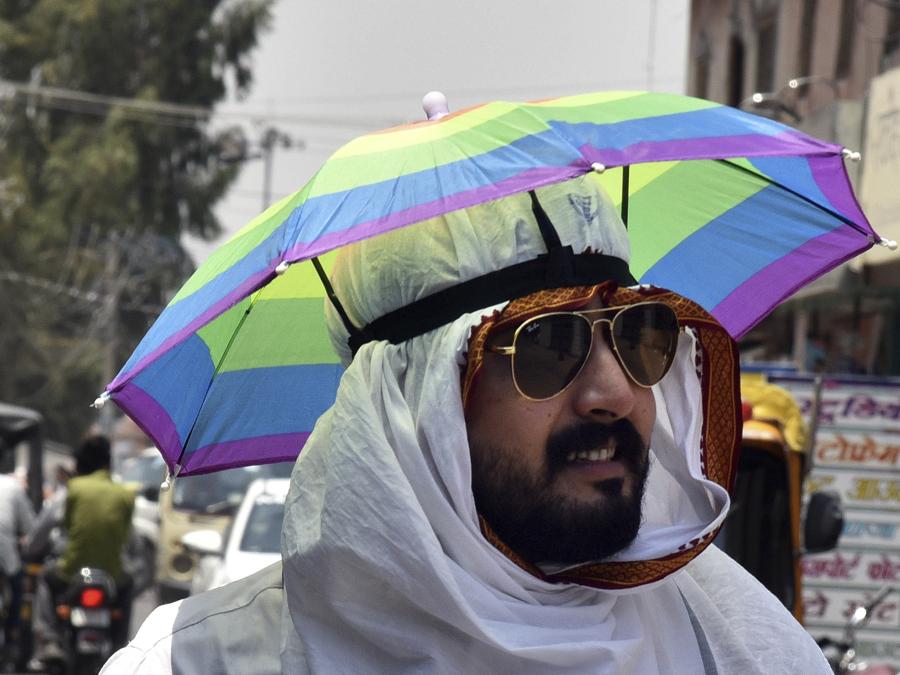 Un uomo indossa un cappello a ombrello in una calda giornata estiva a Bikaner, nello stato indiano occidentale del Rajasthan. (AP Photo/Dinesh Gupta)