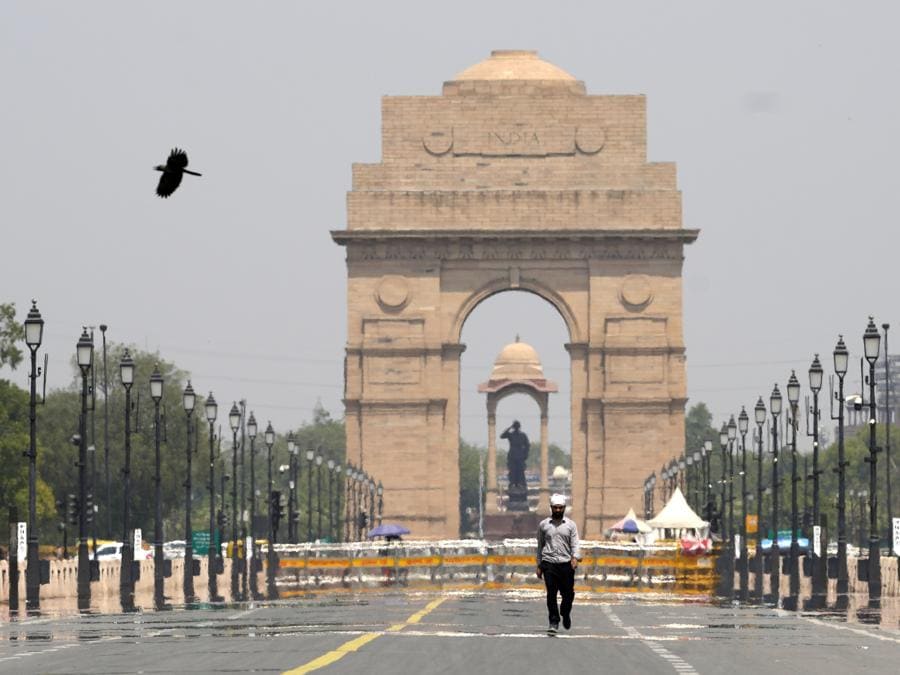 Un uomo passa davanti al monumento dell’India Gate in una calda giornata estiva a Nuova Delhi. (AP Photo/Manish Swarup)