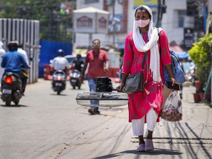 Una donna porta con sé un ventaglio acquistato al mercato in una calda giornata estiva a Guwahati. (AP Photo/Anupam Nath)