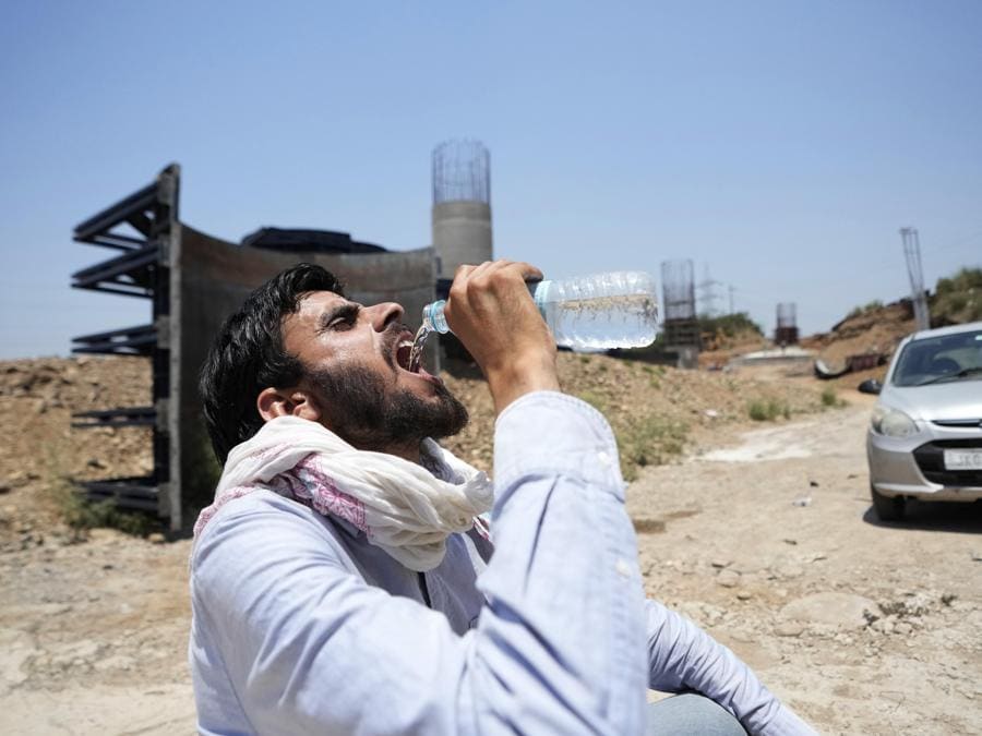 Un uomo beve acqua in una calda giornata estiva a Jammu. (AP Photo/Channi Anand)