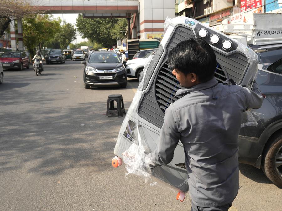 Un uomo trasporta un refrigeratore d’acqua per la sua casa mentre la temperatura aumenta a Nuova Delhi. (AP Photo/Manish Swarup)