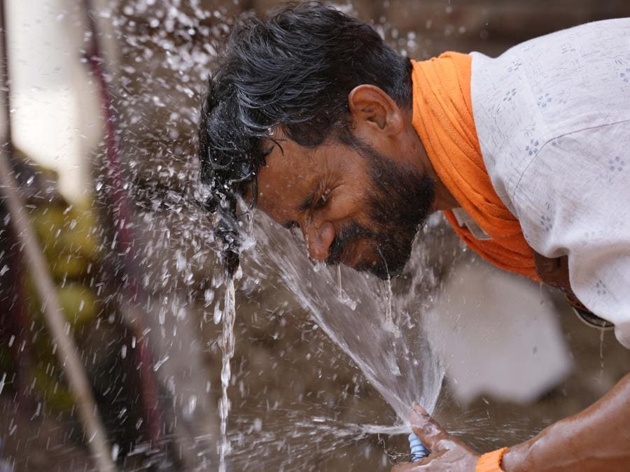 Un uomo si spruzza sul viso l’acqua da un rubinetto lungo la strada per rinfrescarsi in una calda giornata estiva a Lucknow. (AP Photo/Rajesh Kumar Singh)