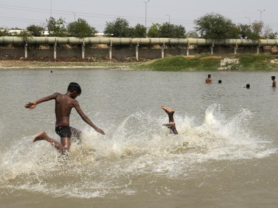 I bambini si rinfrescano in un lago mentre la temperatura aumenta a Nuova Delhi. (AP Photo/Manish Swarup)