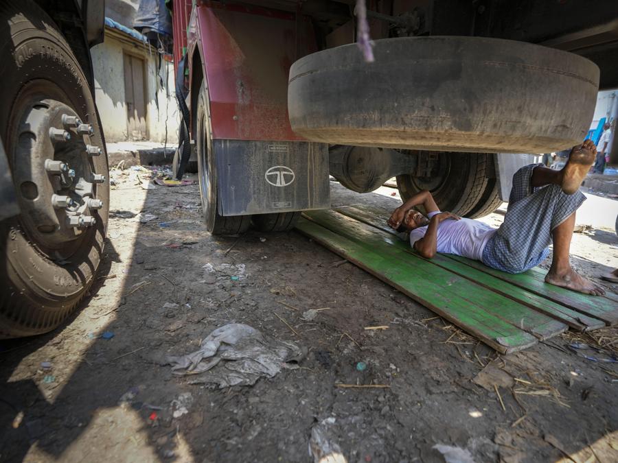 Un uomo dorme sotto un camion in una calda giornata estiva a Guwahati. (AP Photo/Anupam Nath)