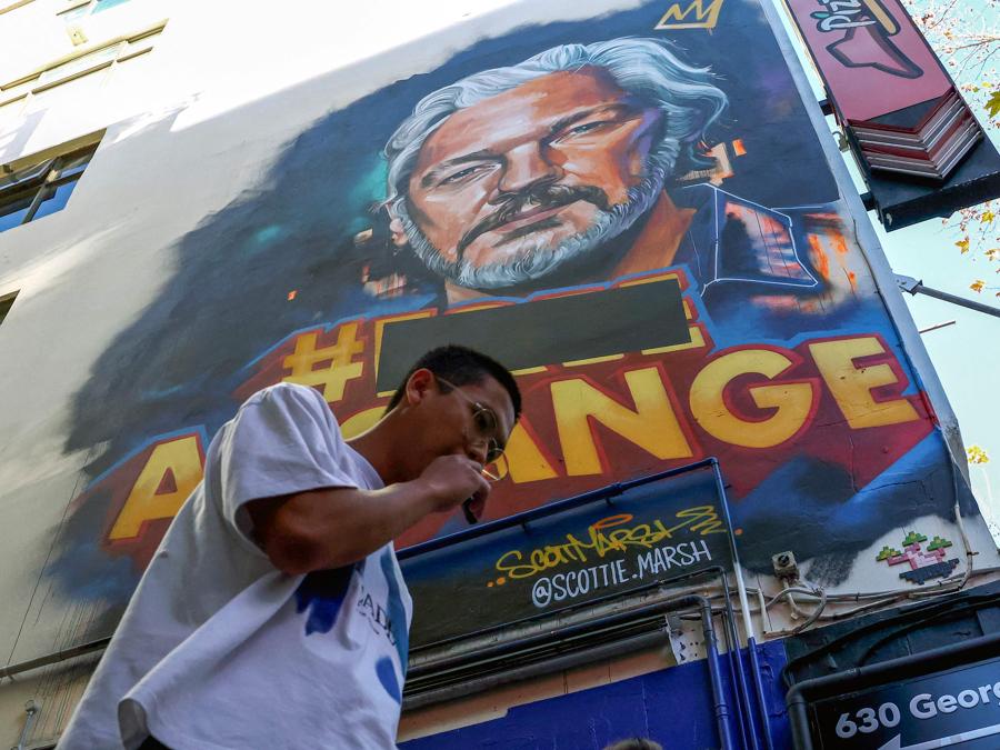 Un uomo passa davanti a un murale del fondatore di Wikileaks Julian Assange su George Street, nel quartiere centrale degli affari di Sydney, il 25 giugno 2024. Julian Assange è stato rilasciato dal carcere il 24 giugno e ha lasciato la Gran Bretagna, ha detto WikiLeaks, dopo aver raggiunto uno storico patteggiamento con le autorità statunitensi che hanno posto fine al suo dramma legale durato anni. (Foto di Saeed KHAN / AFP)+