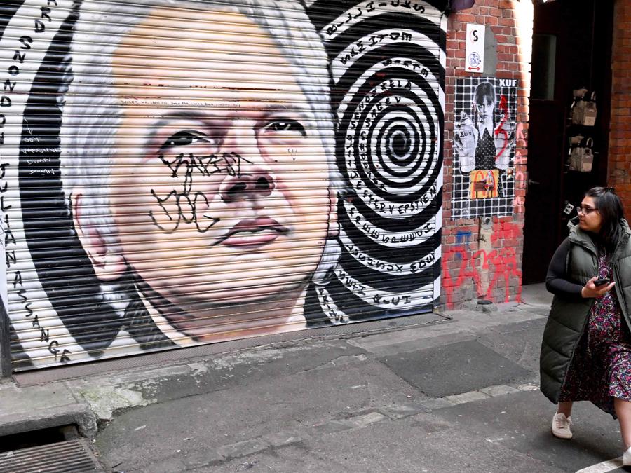 Un turista guarda un murale del fondatore di Wikileaks Julian Assange a Melbourne il 25 giugno 2024. Julian Assange è stato rilasciato dal carcere il 24 giugno e ha lasciato la Gran Bretagna, ha detto WikiLeaks, dopo aver raggiunto uno storico patteggiamento con le autorità statunitensi che ha posto fine a il suo dramma legale durato anni. (Foto di William WEST/AFP)