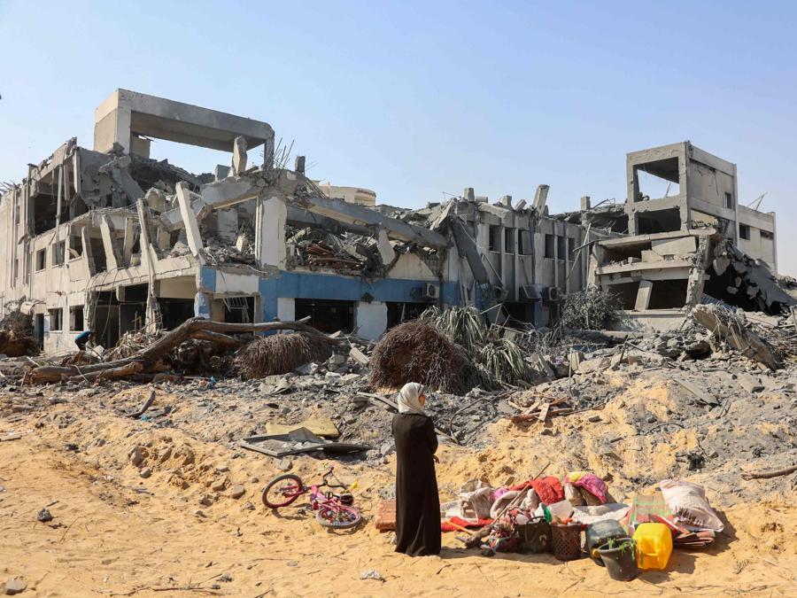 Una donna si guarda intorno mentre recupera oggetti nel complesso edilizio danneggiato dell’Agenzia delle Nazioni Unite per il soccorso e l’occupazione dei rifugiati palestinesi (UNRWA) nel quartiere Al-Sinaa della città occidentale di Gaza. (Photo by Omar AL-QATTAA / AFP)