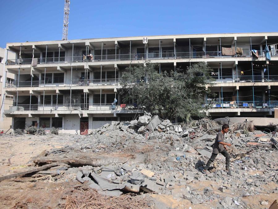 Un uomo cammina sulle macerie del complesso edilizio danneggiato dell’Agenzia delle Nazioni Unite per il soccorso e l’occupazione dei rifugiati palestinesi (UNRWA) nel quartiere Al-Sinaa, nella parte occidentale di Gaza City. (Photo by Omar AL-QATTAA / AFP)