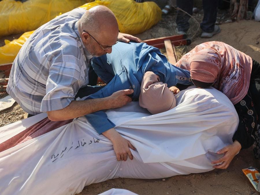 Persone piangono accanto ai corpi dei parenti, trovati sotto le macerie o per strada, prima della loro sepoltura nel quartiere Al-Sinaa, nella parte occidentale di Gaza City. (Photo by Omar AL-QATTAA / AFP)