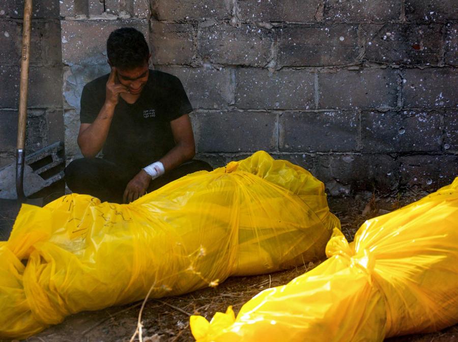 Un uomo piange accanto ai corpi dei parenti, trovati sotto le macerie o per strada, prima della loro sepoltura nel quartiere Al-Sinaa, nella parte occidentale di Gaza City. (Photo by Omar AL-QATTAA / AFP)