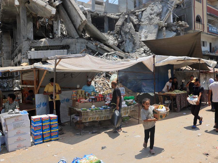 Persone acquistano generi di prima necessità in un mercato improvvisato a Nuseirat, nel centro della Striscia di Gaza. (Photo by Eyad BABA / AFP)