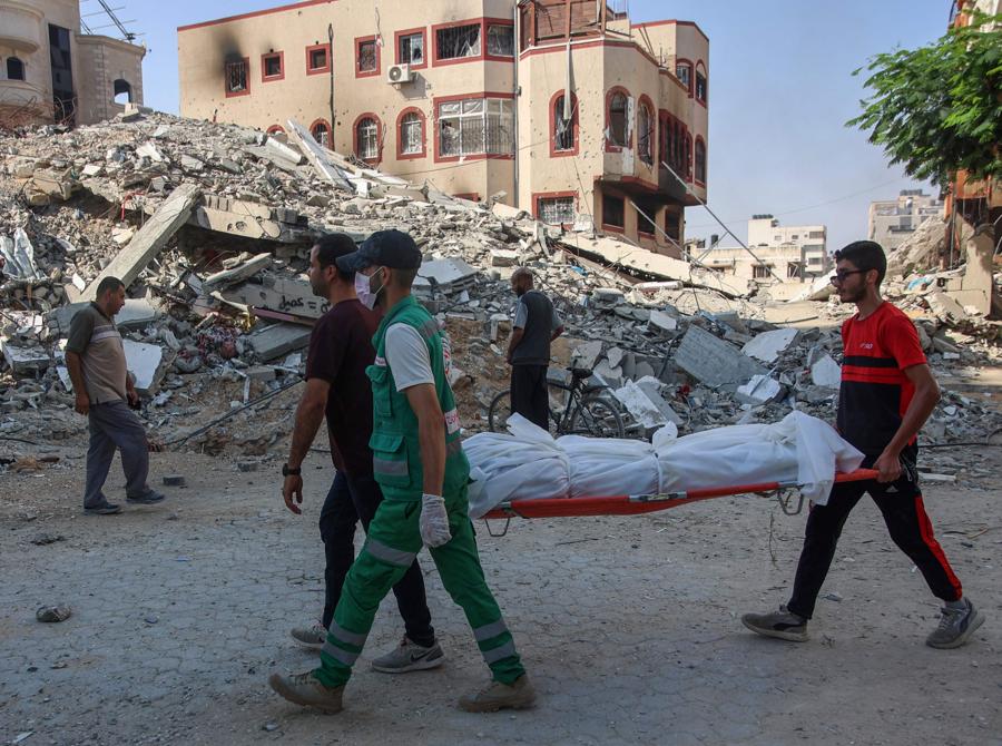 Persone evacuano i corpi trovati sotto le macerie o per strada nel quartiere Al-Sinaa, nella parte occidentale di Gaza City. (Photo by Omar AL-QATTAA / AFP)