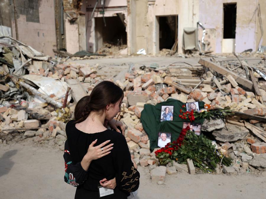 Gli operatori ospedalieri in lutto davanti a un memoriale improvvisato con i ritratti delle vittime esposti sulle rovine di uno degli edifici sanitari dell’ospedale pediatrico di Okhmatdyt distrutto dall’esplosione di un razzo, a Kiev. (Photo by Anatolii STEPANOV / AFP)