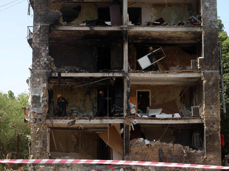Personale di emergenza e di soccorso ripuliscono  oggetti dagli appartamenti di un edificio distrutto da un attacco missilistico, a Kiev. (Photo by Anatolii Stepanov / AFP)