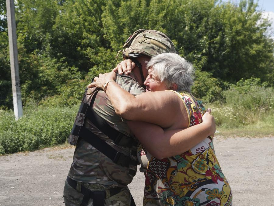 Una donna del posto abbraccia un agente di polizia a Bilyi Kolodiaz, regione di Kharkiv. (AP Photo/Andrii Marienko)