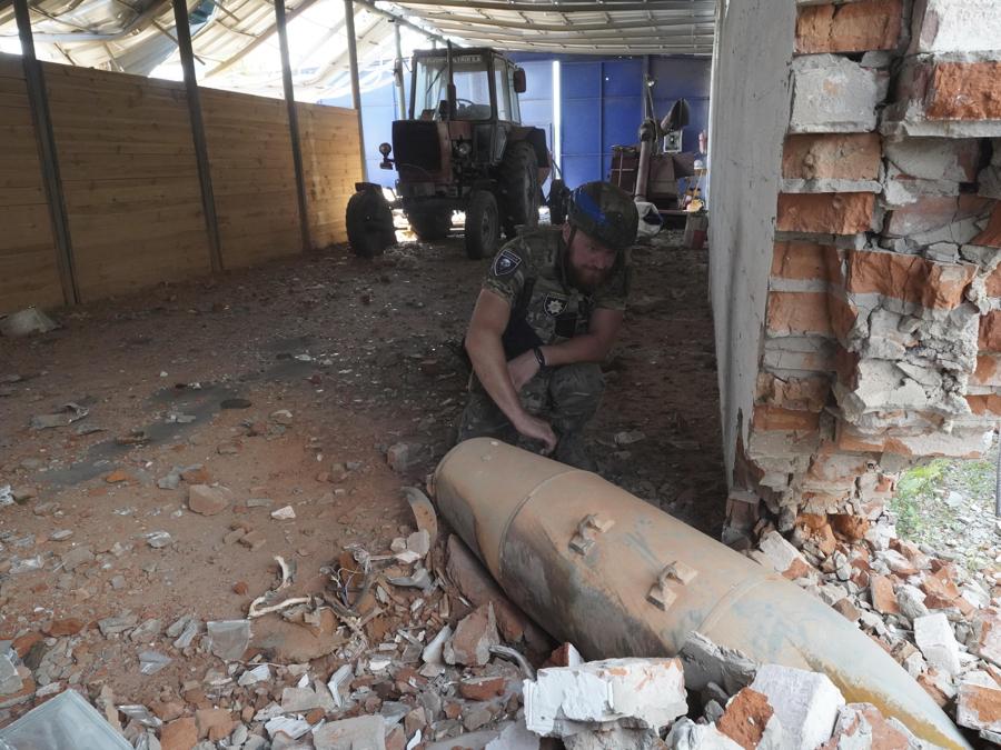 Un agente di polizia ispeziona una bomba inesplosa da 250 chilogrammi (550 libbre) dopo un attacco aereo russo sul magazzino agricolo di Bilyi Kolodiaz, regione di Kharkiv. (AP Photo/Andrii Marienko)