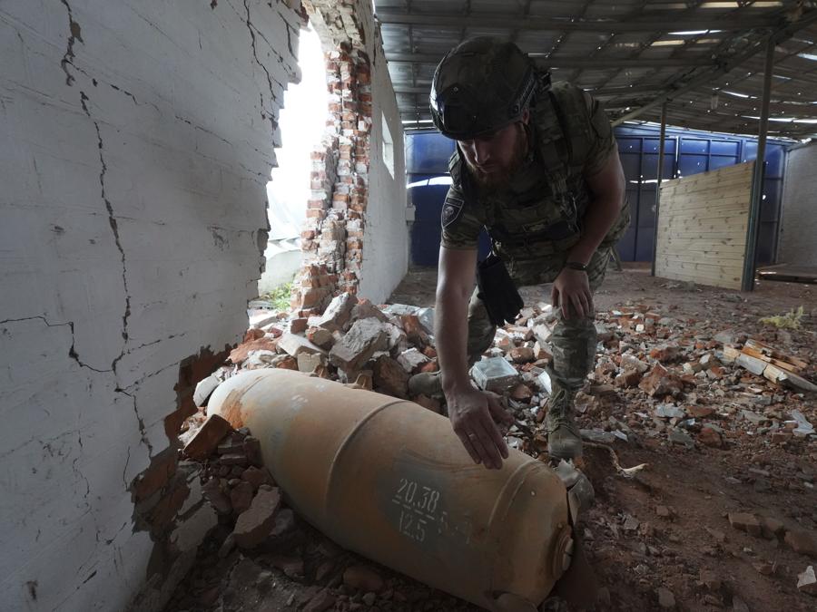 Un agente di polizia ispeziona una bomba inesplosa da 250 chilogrammi (550 libbre) dopo un attacco aereo russo sul magazzino agricolo di Bilyi Kolodiaz, regione di Kharkiv. (AP Photo/Andrii Marienko) 