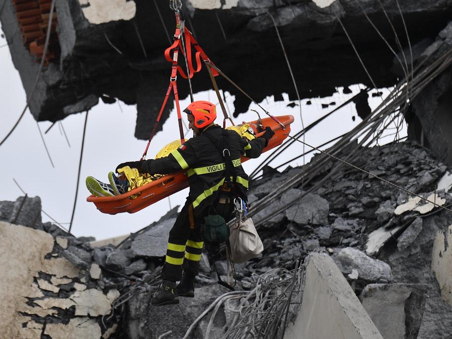 Soccorritori al lavoro per recuperare un ferito dopo il crollo del  ponte Morandi. ANSA/ LUCA ZENNARO