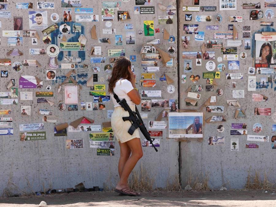 A Reim, nel sud di Israele, una donna israeliana guarda adesivi e poster su un rifugio antiaereo allestito nel luogo del Nova festival  dove i partecipanti alla festa sono stati uccisi e rapiti, a 300 giorni dall’attacco mortale del 7 ottobre da parte di uomini armati di Hamas provenienti da Gaza. (REUTERS/Amir Cohen)