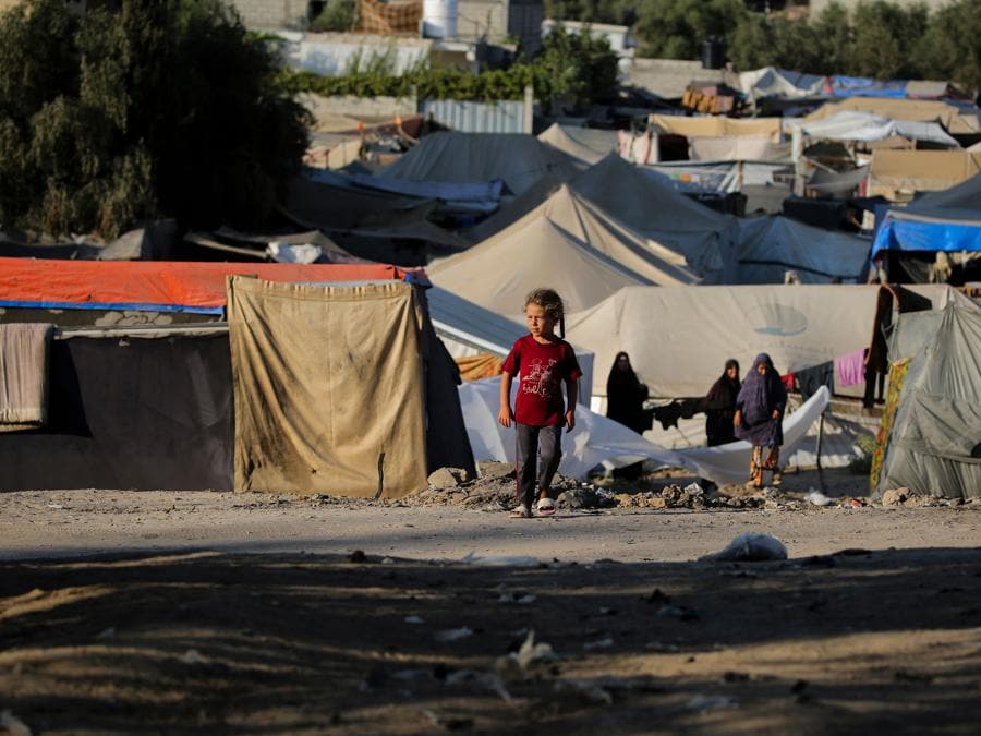 Un bambino cammina vicino a rifugi di fortuna nel campo profughi palestinese di al-Maghazi, nel centro della Striscia di Gaza. (Photo by Eyad Baba / AFP)