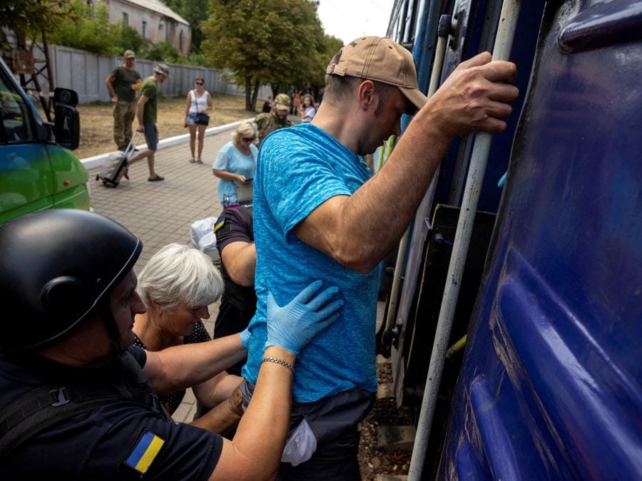 Volontari di East SOS aiutano un uomo a salire su un treno alla stazione ferroviaria di Pokrovsk. Le persone vengono  evacuate mentre le forze russe avanzano in prima linea nella regione di Donetsk. (REUTERS/Thomas Peter)