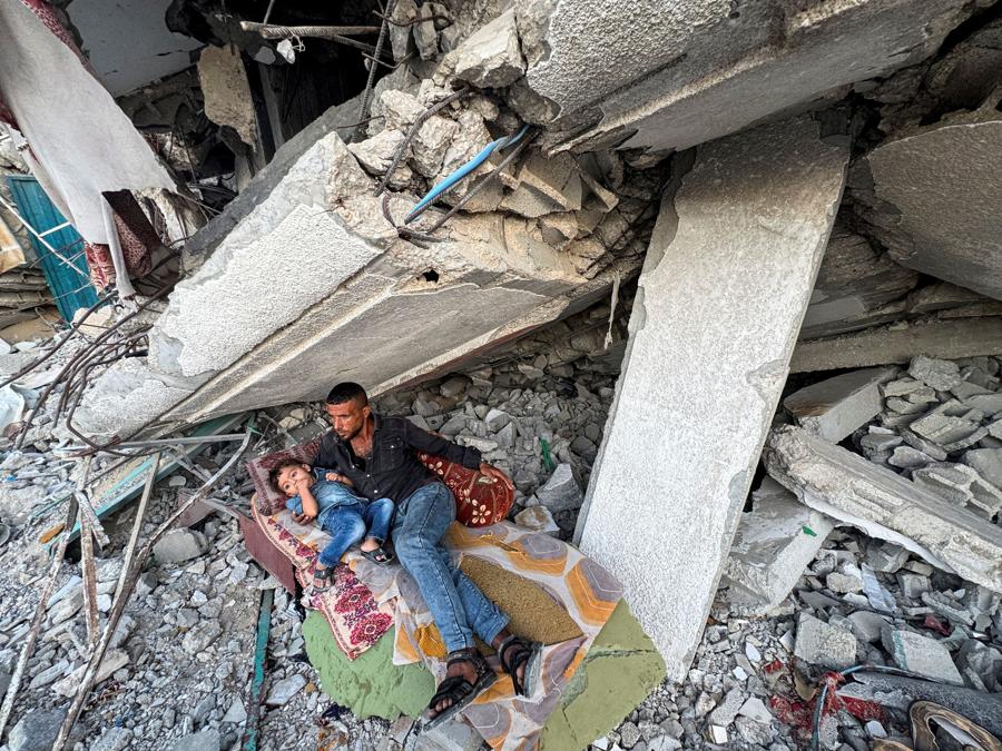 Un uomo palestinese riposa con il figlio sotto le macerie di una casa distrutta dagli attacchi israeliani a Khan Younis, nel sud della Striscia di Gaza. (Reuters)