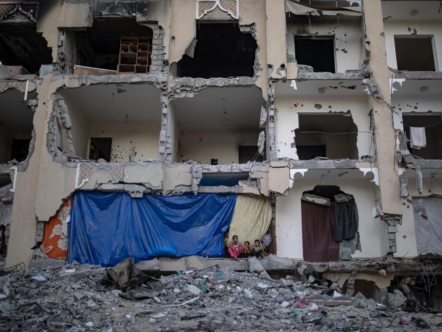 Bambini palestinesi siedono sulle macerie della loro casa nel campo profughi di Khan Yunis, nel sud della Striscia di Gaza. EPA/HAITHAM IMAD