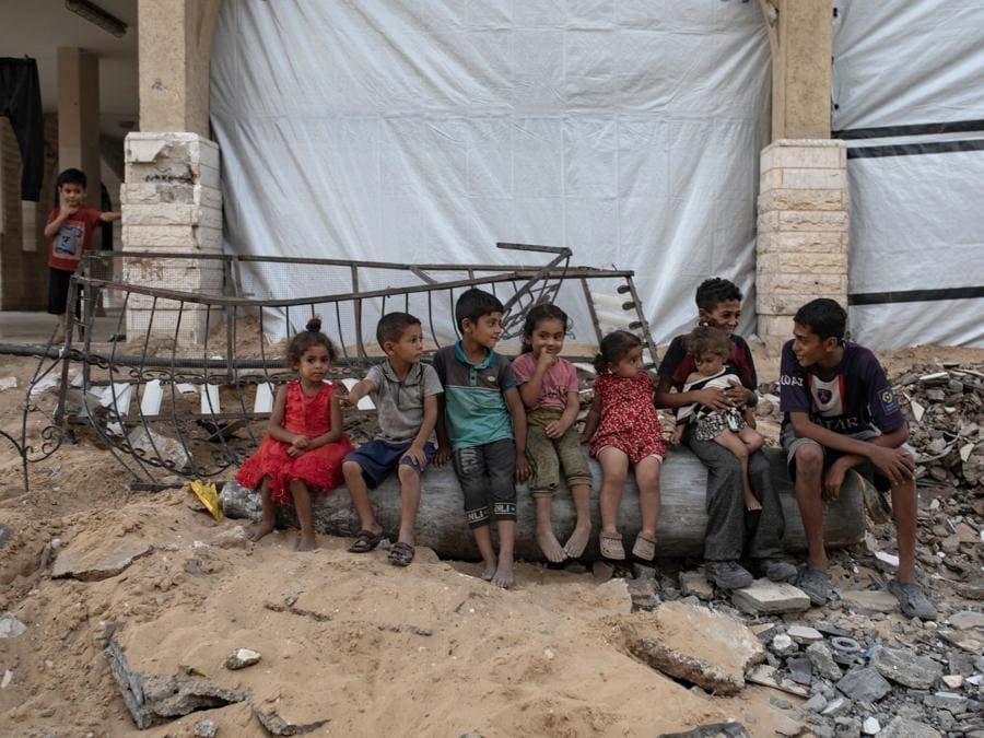 Un gruppo di bambini palestinesi siede su un missile israeliano inesploso tra le macerie di un edificio distrutto nel campo profughi di Khan Yunis, nel sud della Striscia di Gaza. EPA/HAITHAM IMAD