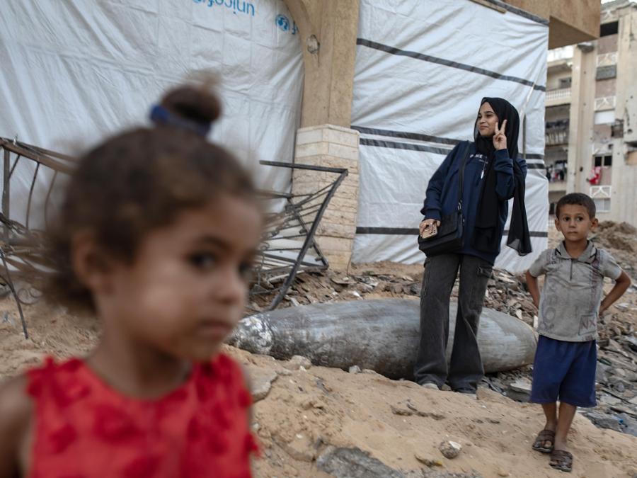 Bambini palestinesi giocano accanto a un missile israeliano inesploso tra le macerie di un edificio distrutto nel campo profughi di Khan Yunis, nel sud della Striscia di Gaza. EPA/HAITHAM IMAD
