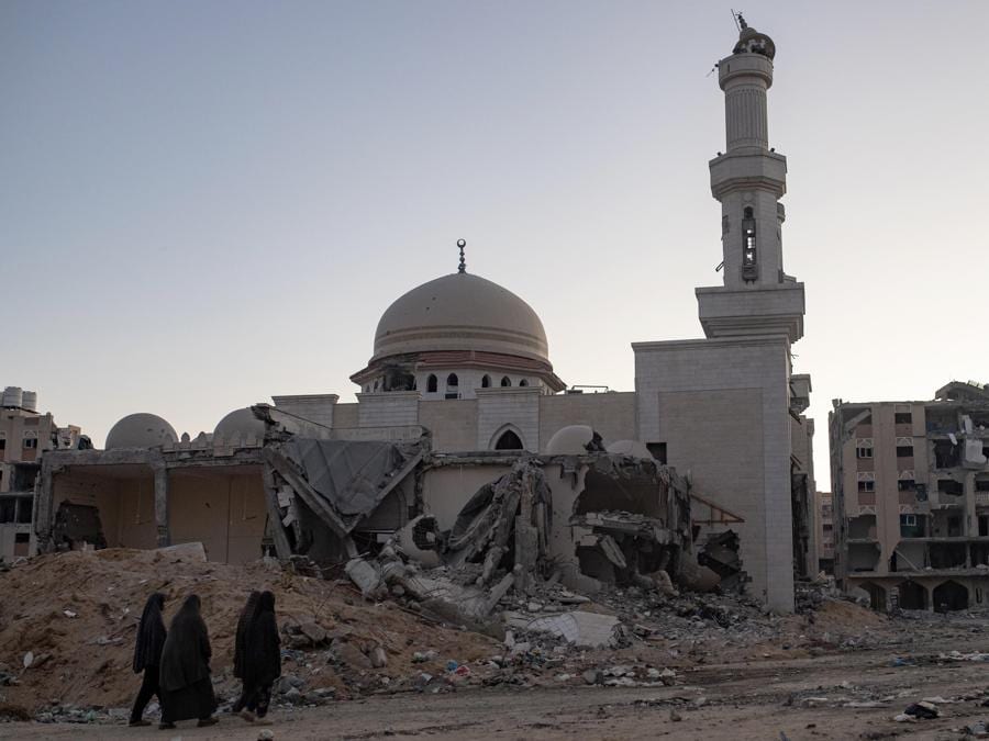 Donne palestinesi camminano tra le macerie degli edifici distrutti dalle forze israeliane nel campo profughi di Khan Yunis, nel sud della Striscia di Gaza. EPA/HAITHAM IMAD